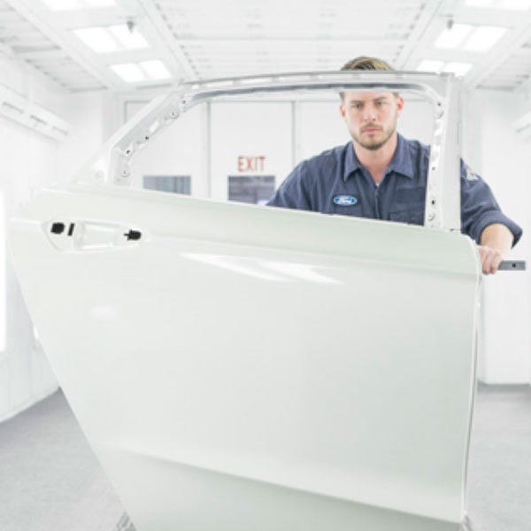 Ford Collision Repair technician holding a car door.